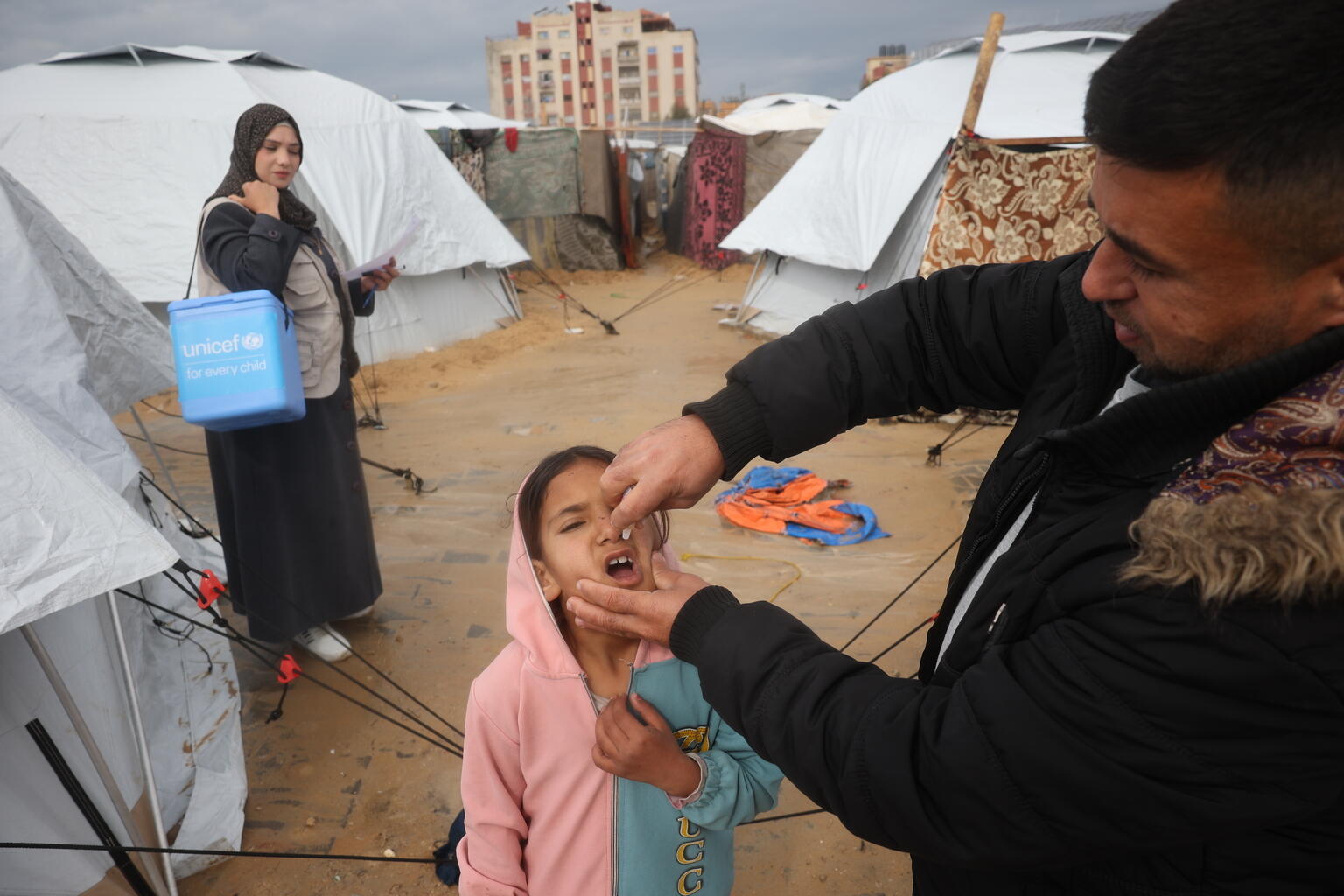 Während einer großen Impfaktion in Gaza impft ein Helfer ein Mädchen gegen Polio.