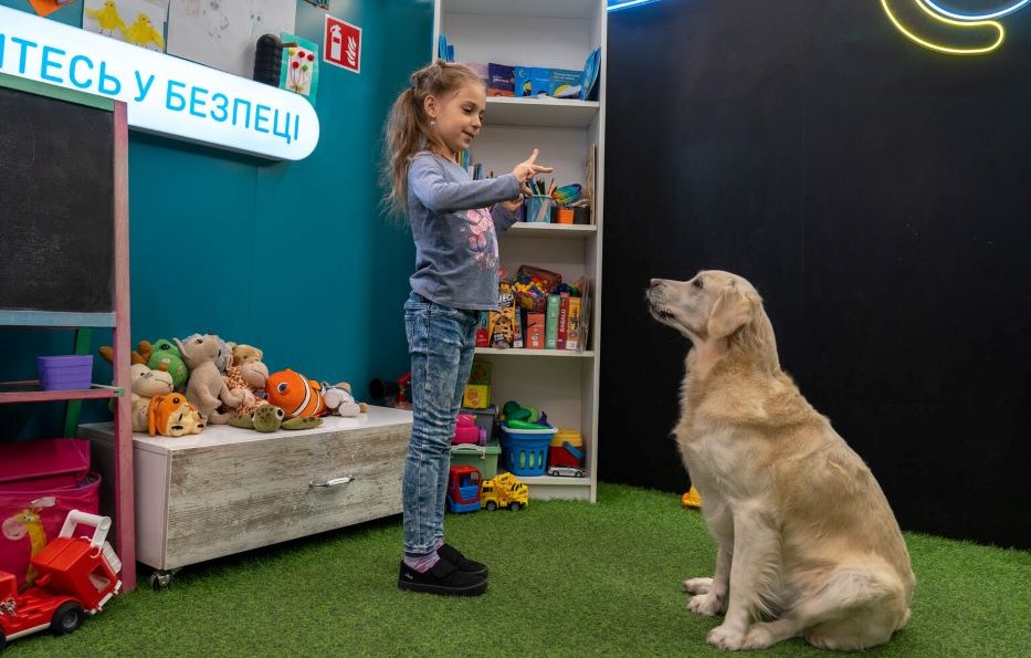 In einer Anlaufstelle für Kinder spielt die siebenjährige Adelina mit einem Therapiehund.